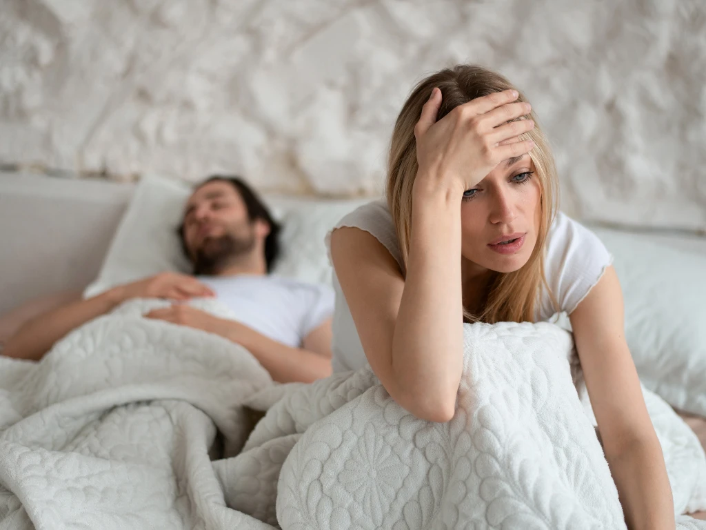 woman looking frustrated with man sleeping in the bed